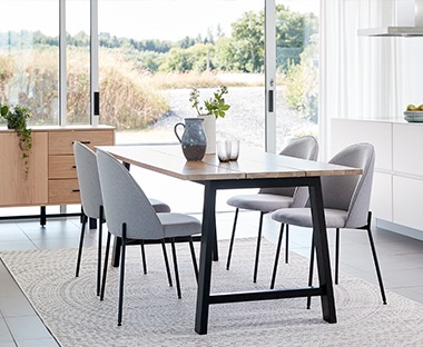Wooden plank top table with sturdy black metal legs with grey upholstered dining chairs with matching metal legs