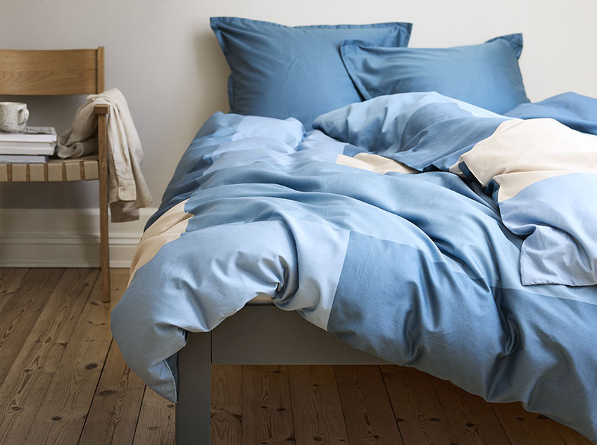 Bed with Cotton bedding in shades of blue and sand 