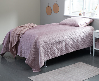 Pink quilted patterned bed throw covering single bed