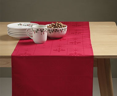 Red table runner with Christmas dishes on