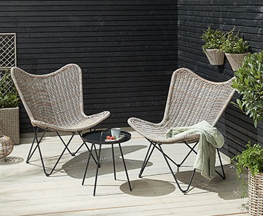 A pair of garden lounge chairs in natural woven polyrattan