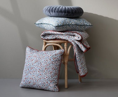 Floral print plush feather filled cushions with red and blue piping. 