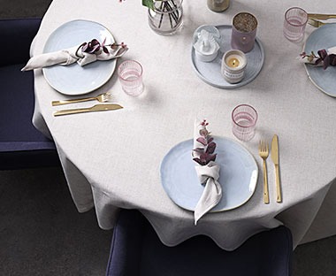 Dinner table set with plates cutlery glasses and table linen