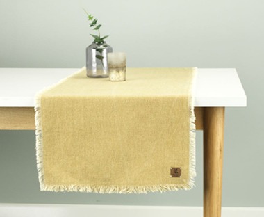 A contemporary yellow table runner with fringe edging 