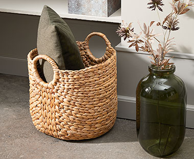 Hyacinth storage basket with handles next to a tall green vase