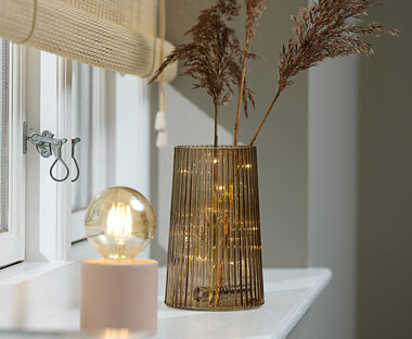 Brown glass vase with string lights inside with pink lamp and exposed bulb