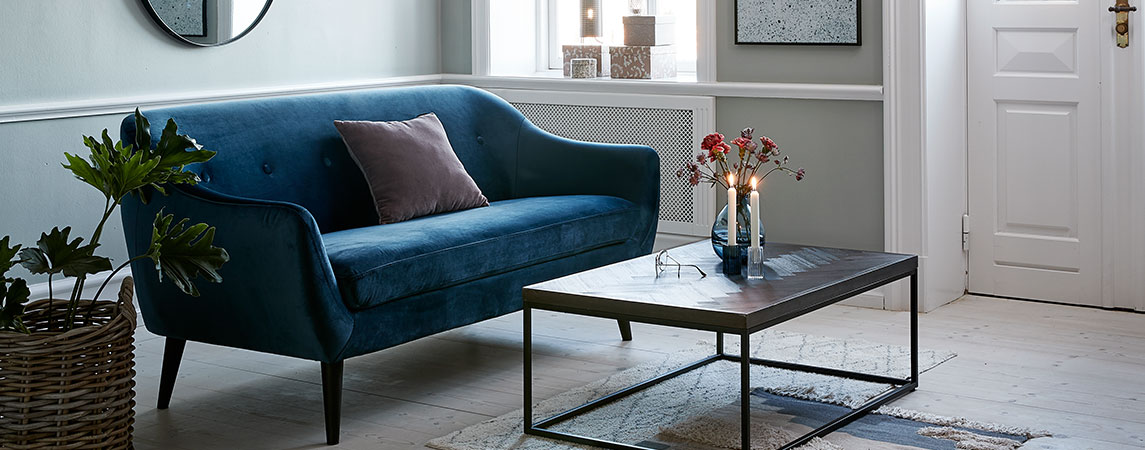 Living room with a blue velvet sofa and a coffee table with lit candles 