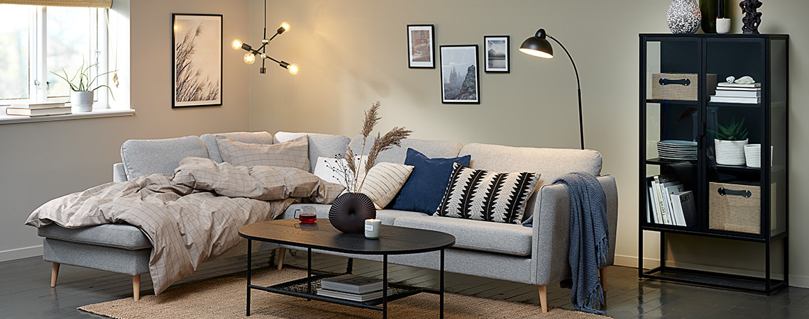 Living room “hygge” with big corner sofa, duvet, cushions and lighting