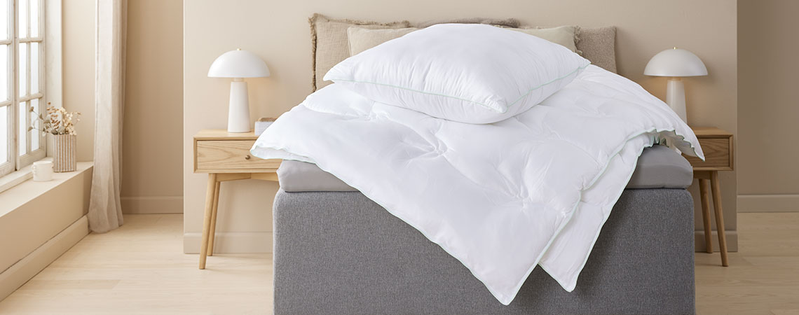 Duvet and pillow with cover in bamboo viscose fabric on top of bed in light bedroom