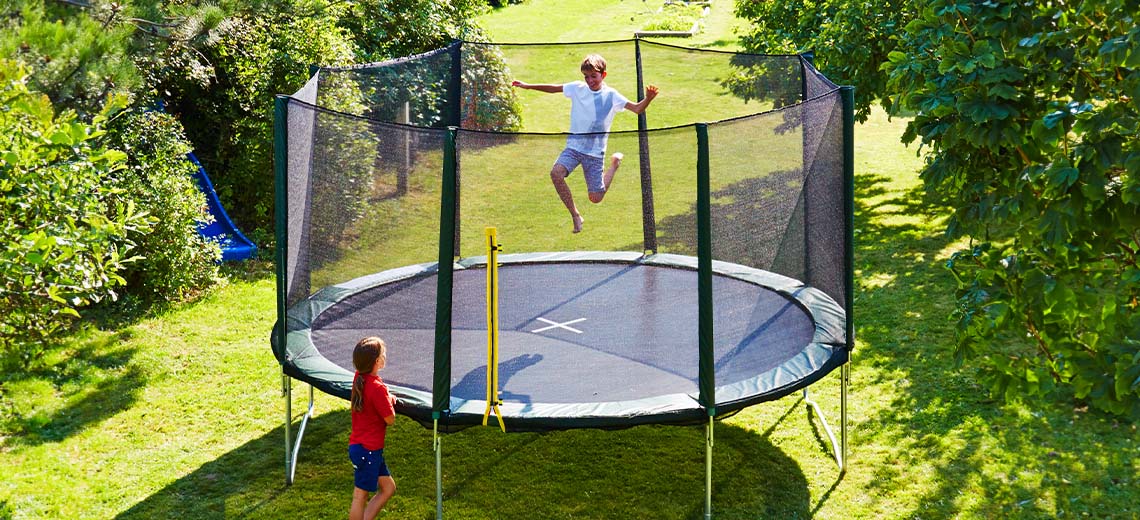 Children playing on a large trampoline in the garden 