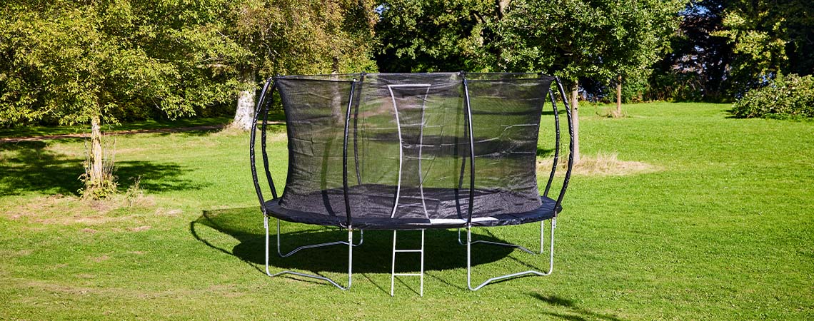 Large trampoline on green lawn in garden 