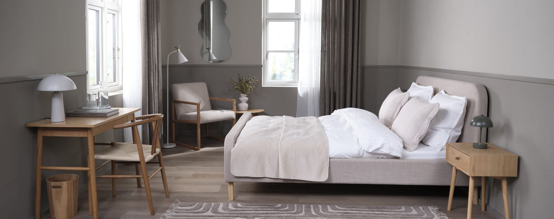 Upholstered bed frame in a bedroom with office space