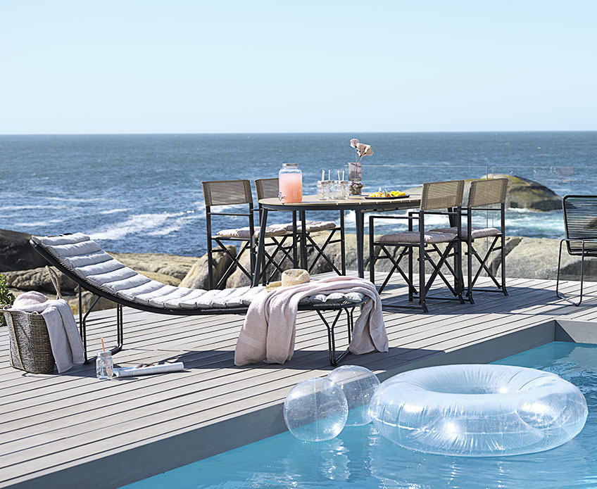 Outdoor garden furniture by a swimming pool, close to the ocean 