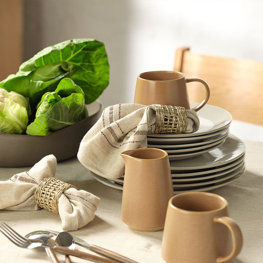 Tableware: White dinner plates and white dessert plates, mug, milk jug, cloth napkins with napkin rings, and salad bowl on dining table