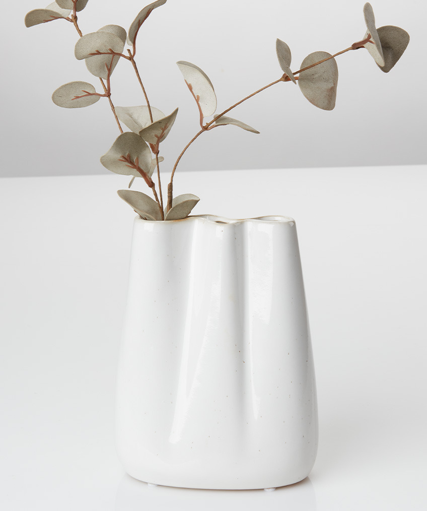 White vase with organic lines and wavy edges and artificial twig