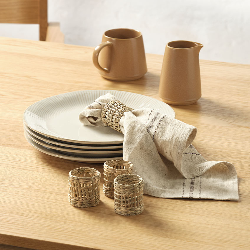 White fluted dinner plates, milk jugs, cloth napkin, and napkin rings on dining table