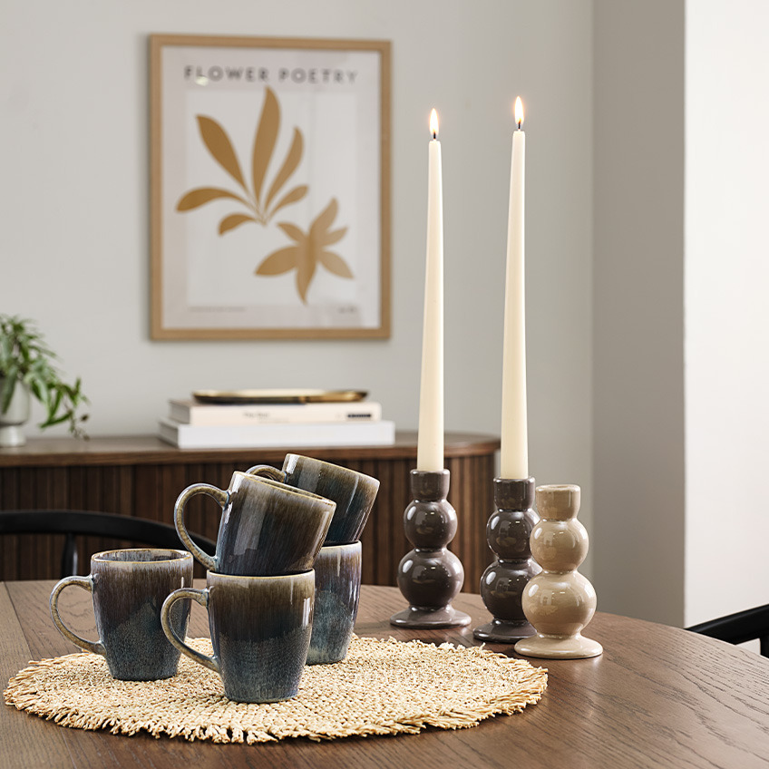 Bulbous candle holder in earthen shades of brown and sand and mugs with reactive glaze