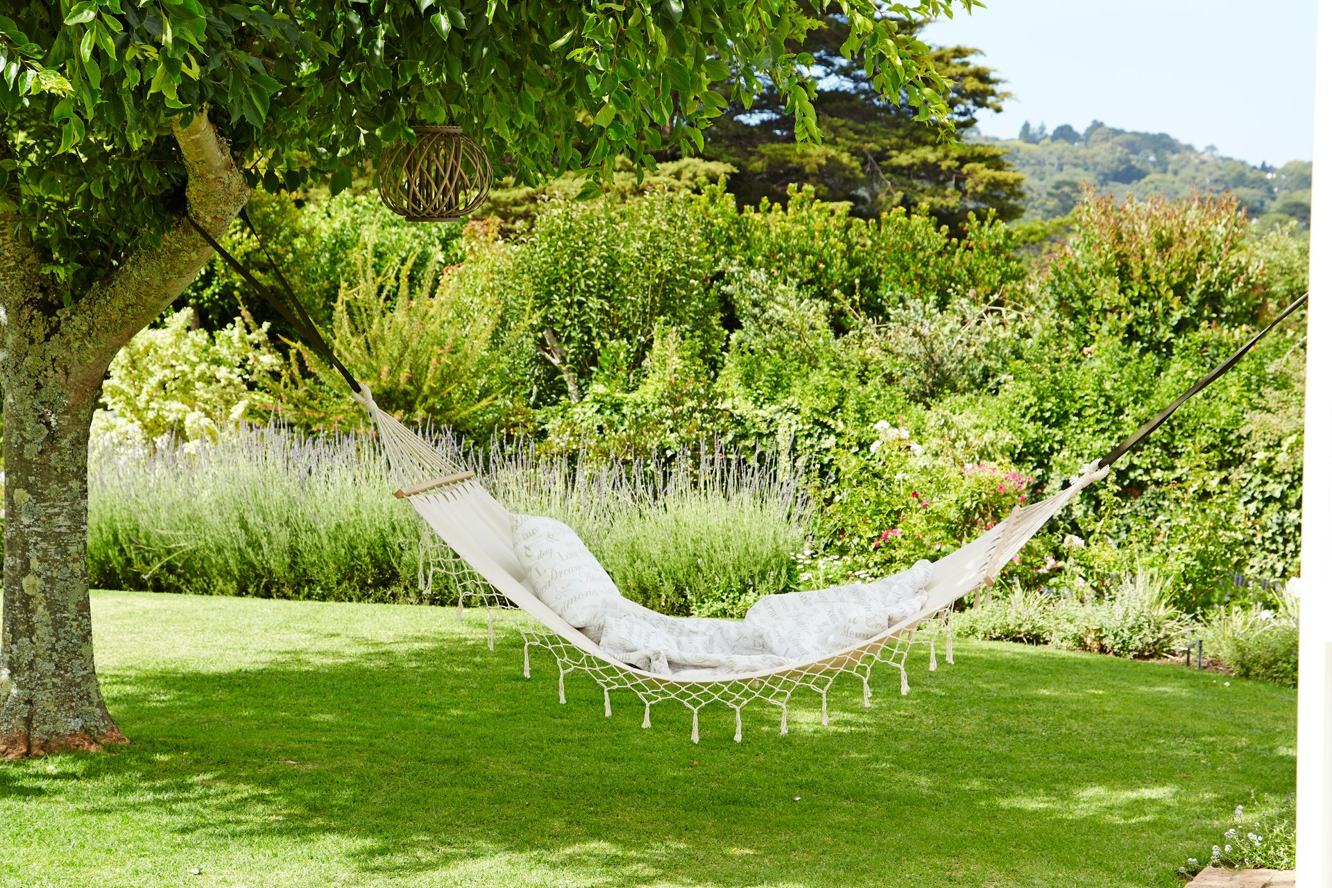 White hammock suspended between two trees in garden