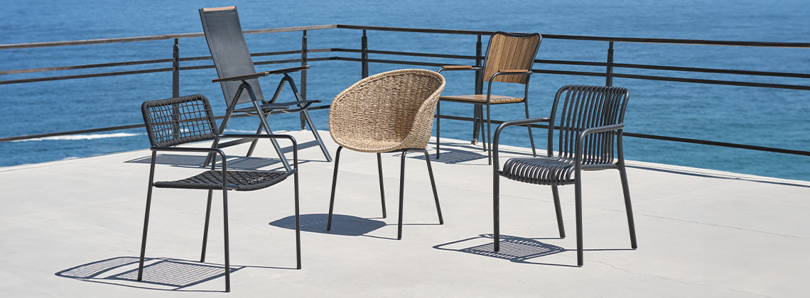 A selection of five garden chairs on patio by the sea