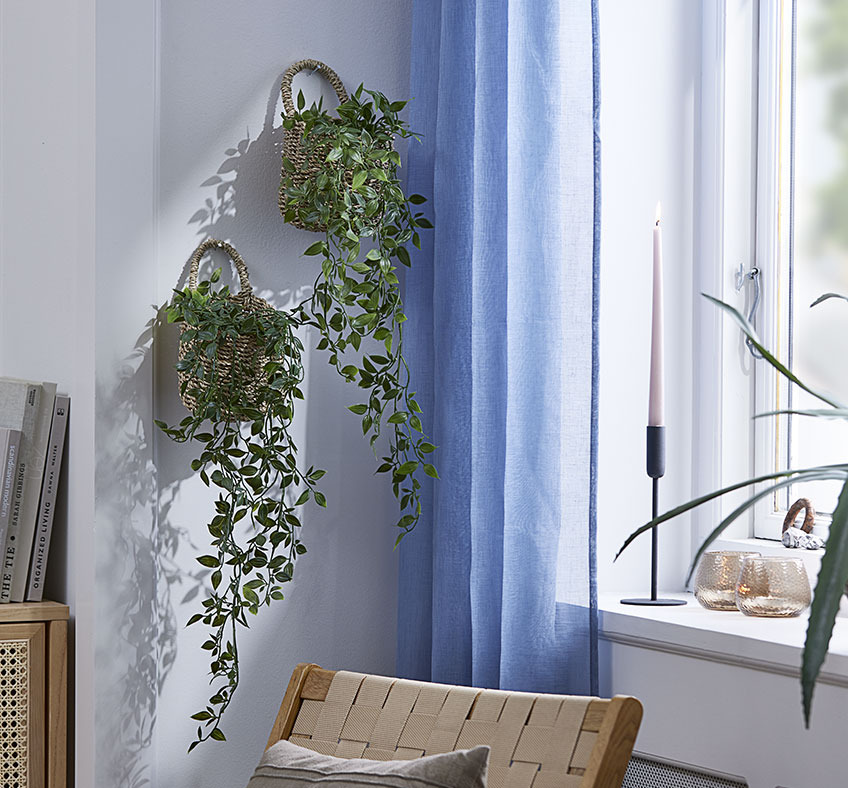 Two baskets with artificial plants hanging on a living room wall