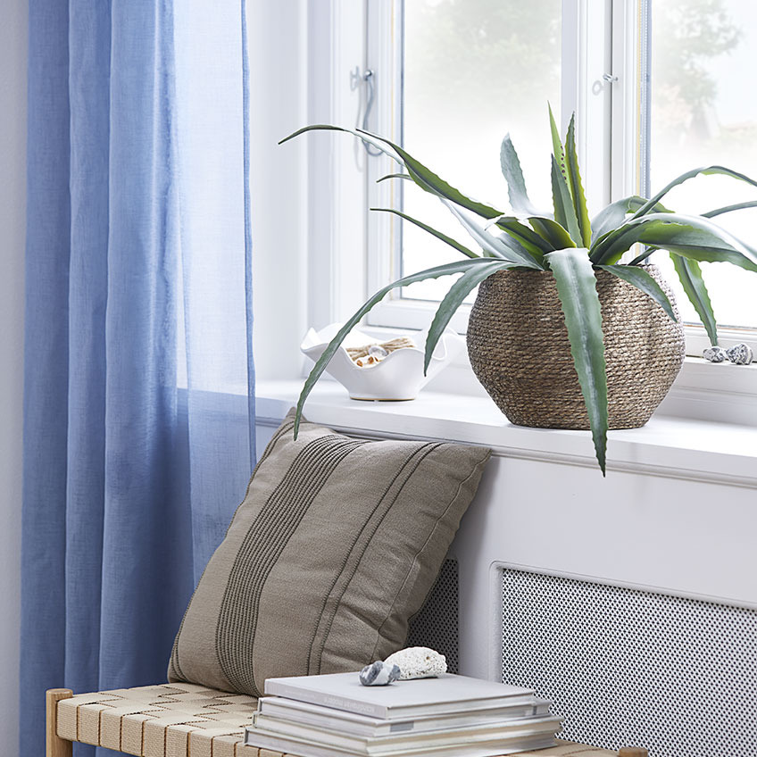 Windowsill with artificial plant in wicker plant pot