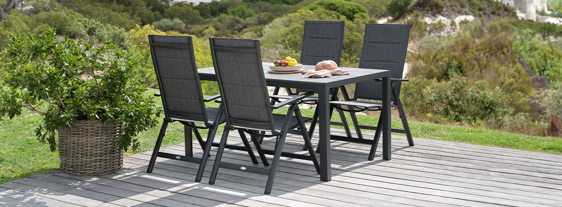 Garden lounge set with garden table and chairs in garden next to plant