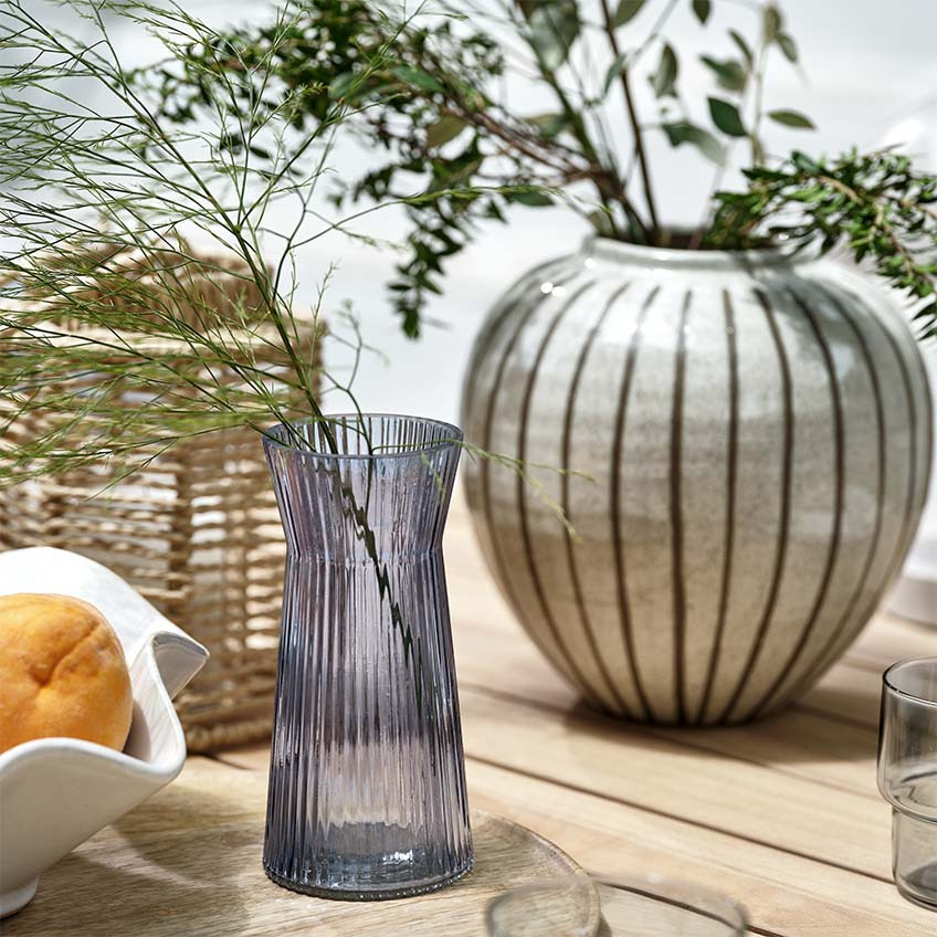 Vases, lantern, and bowl on wooden garden table outdoors 