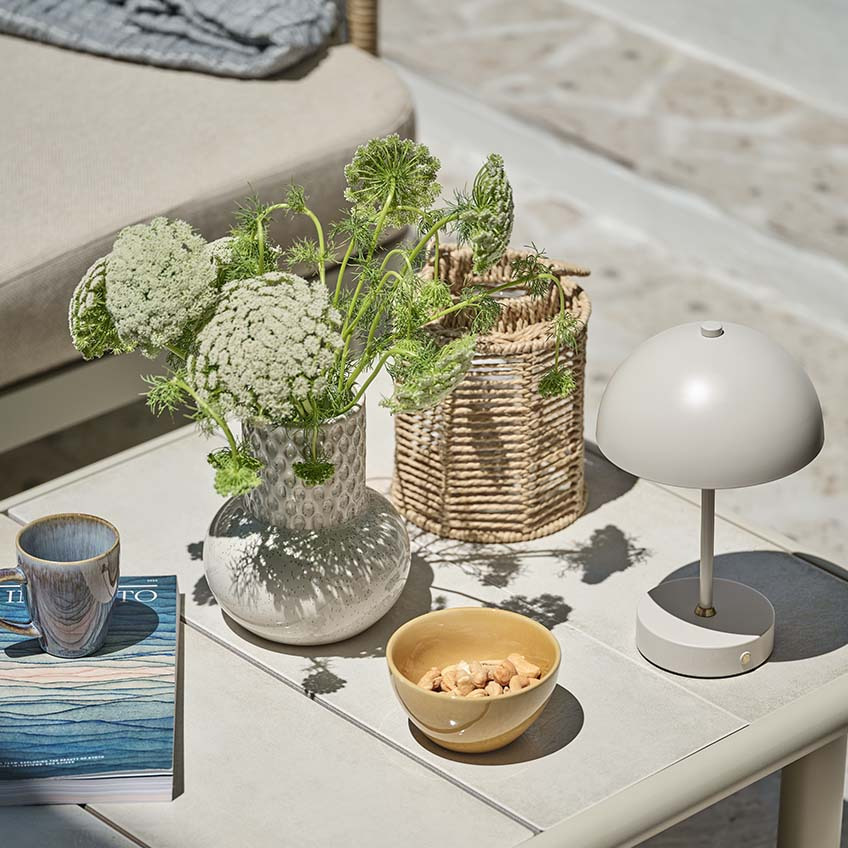 Small garden table with various decor, including small battery lamp, vase, and lantern
