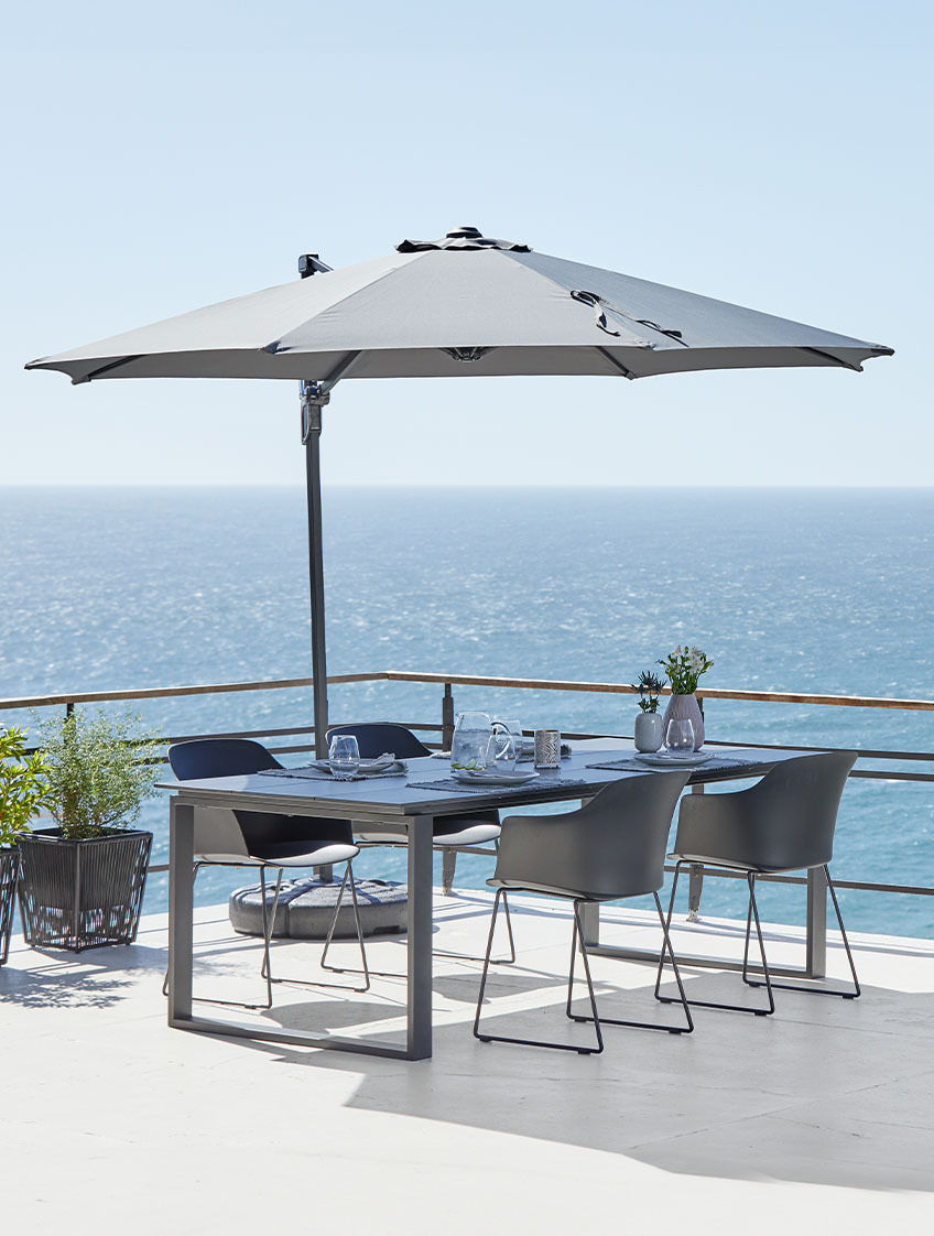 Large hanging parasol and garden table and chairs on patio by the ocean