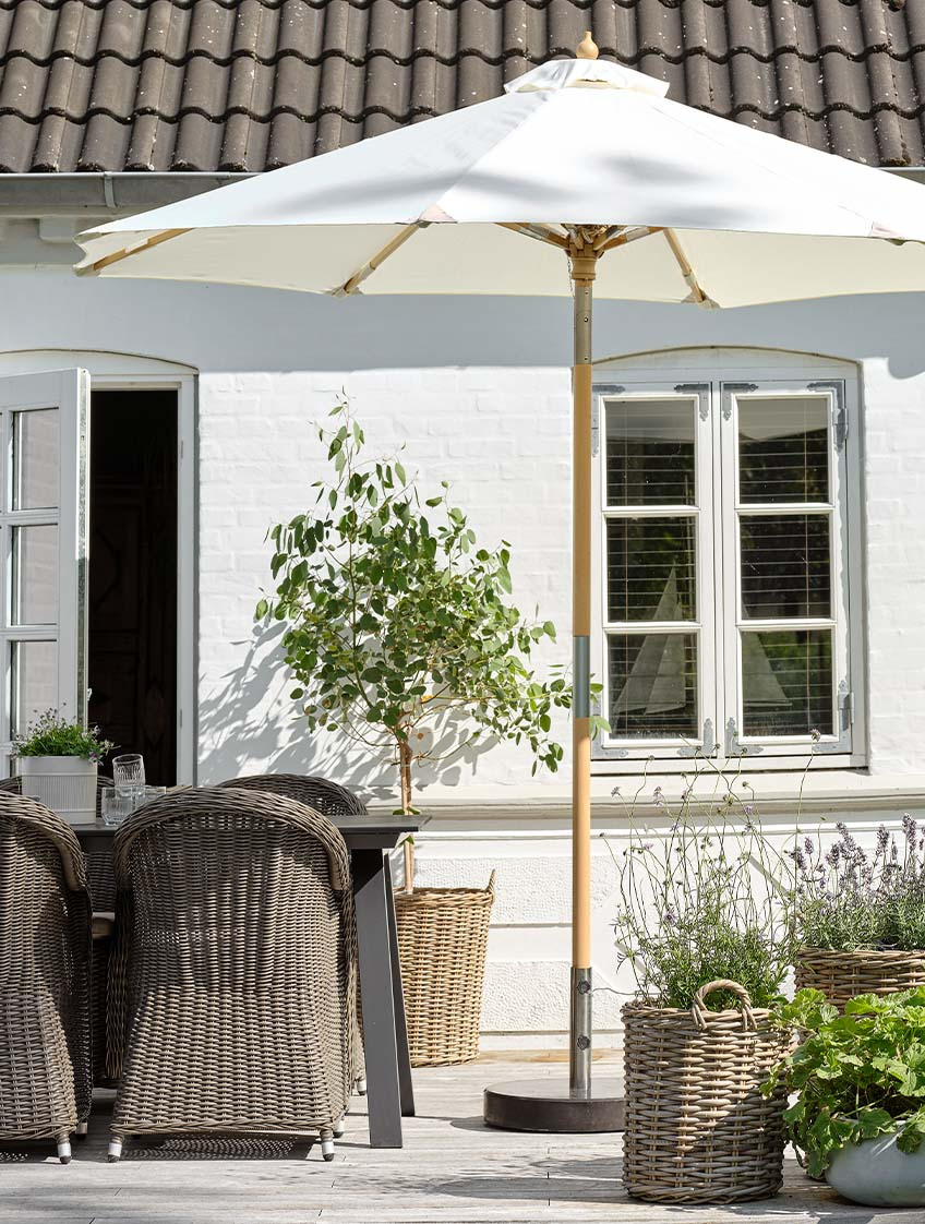 Classic off-white garden parasol on patio with garden table and garden chairs