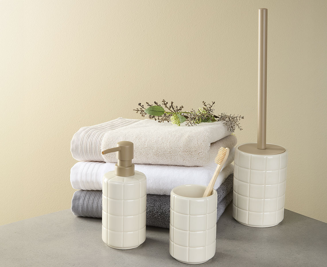 Stack of towels with soap dispenser, toothbrush holder and toilet bush 