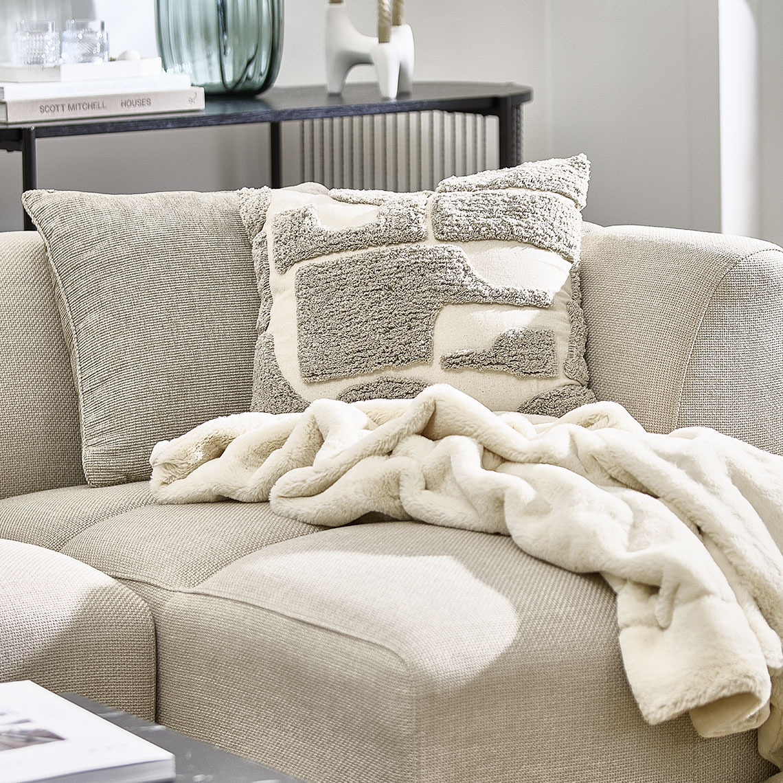 Beige sofa with cushions and a throw 