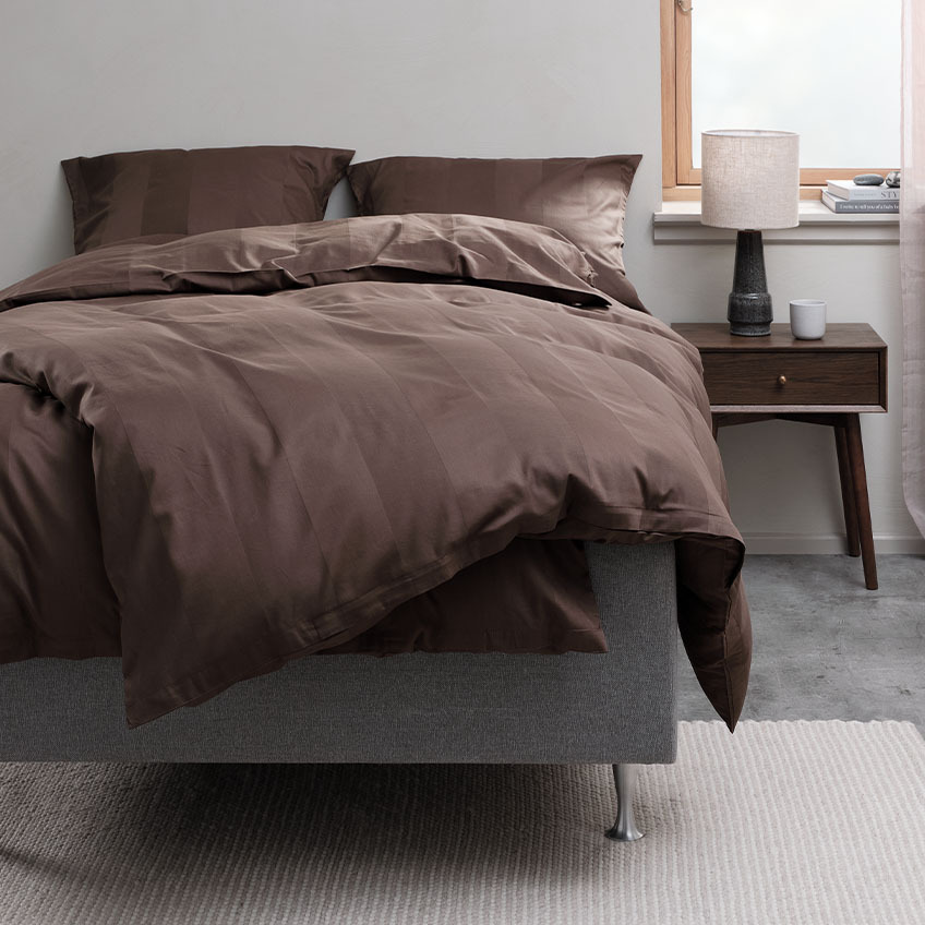 Chocolate brown duvet cover set and cotton bedding on bed in bedroom 