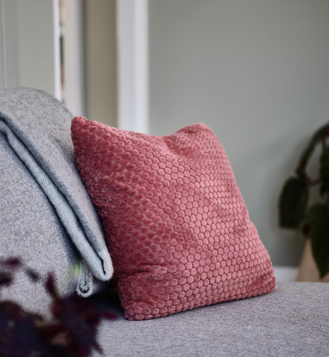 pink textured cushion on grey sofa