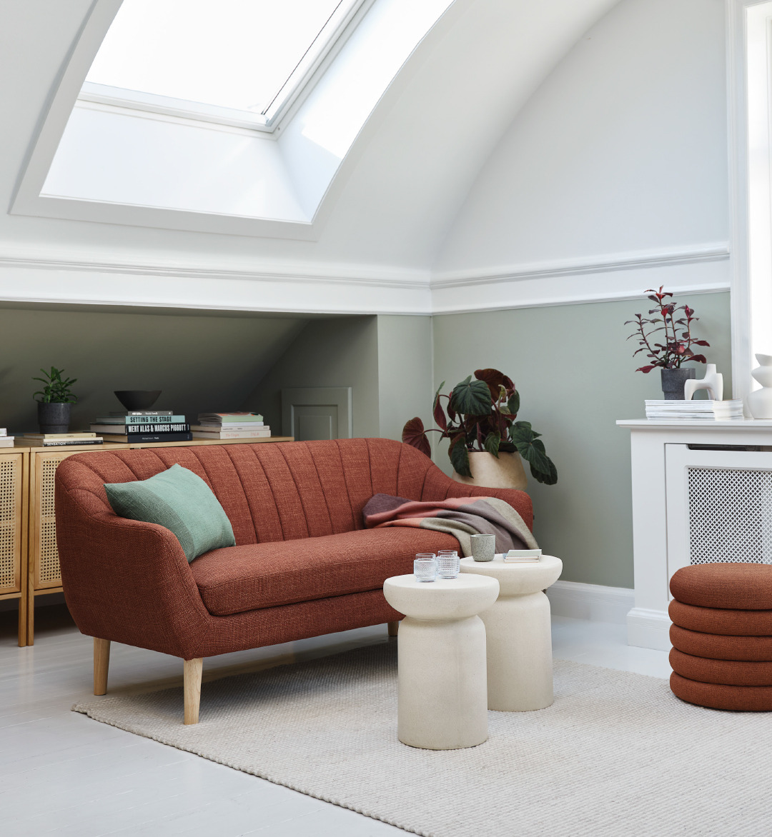 red textured sofa with green pillow and cream pedestals