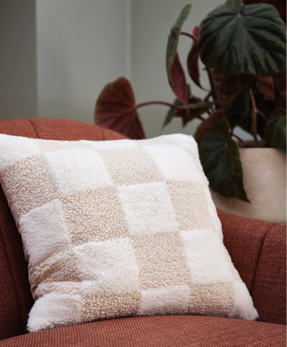 cream checkered pillow on red textured sofa