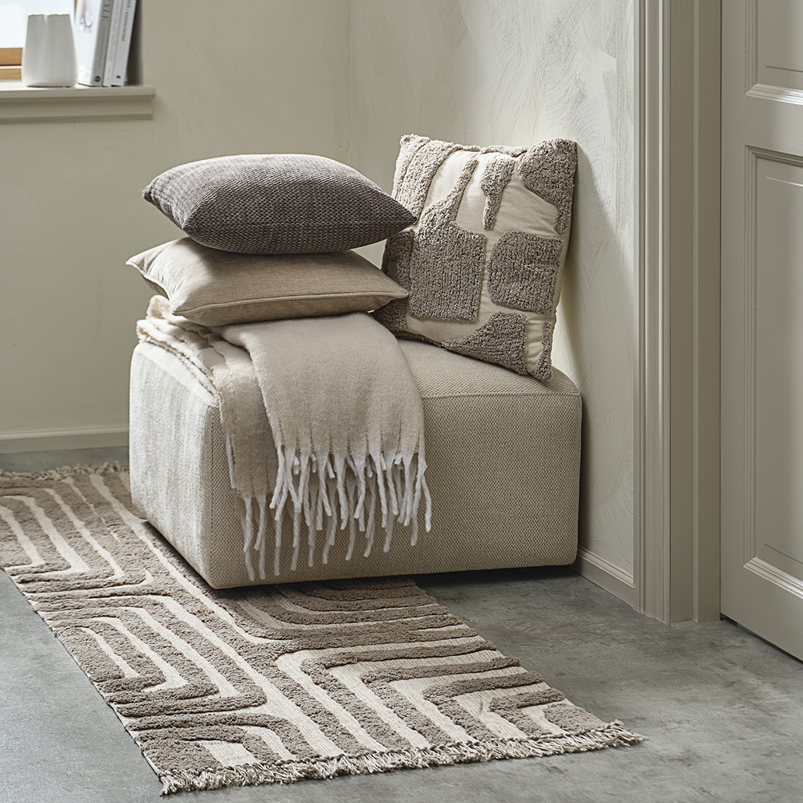 Tufted rug in front of pouffe with matching cushions and throw