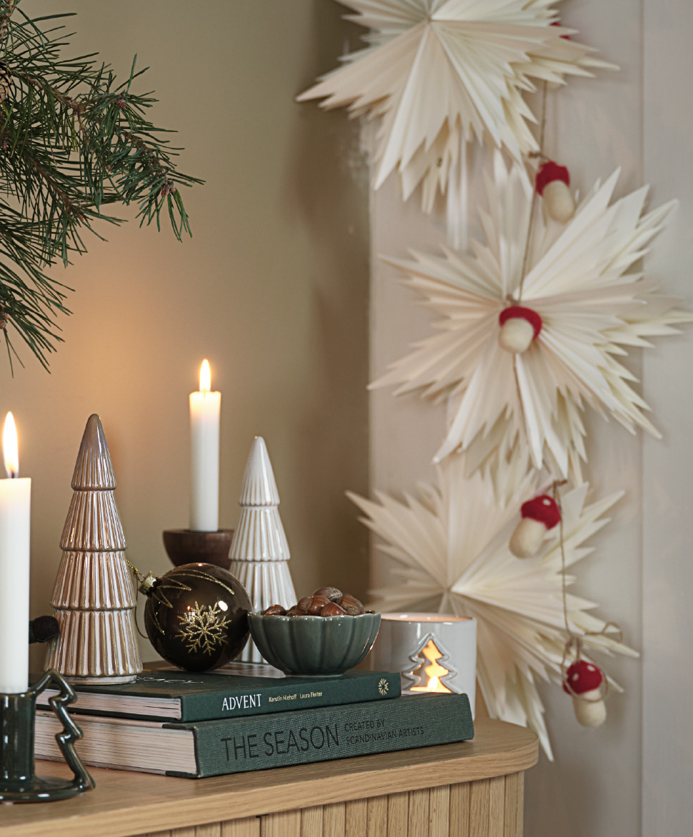 A sideboard with beautiful Christmas decorations and paper stars along the wall