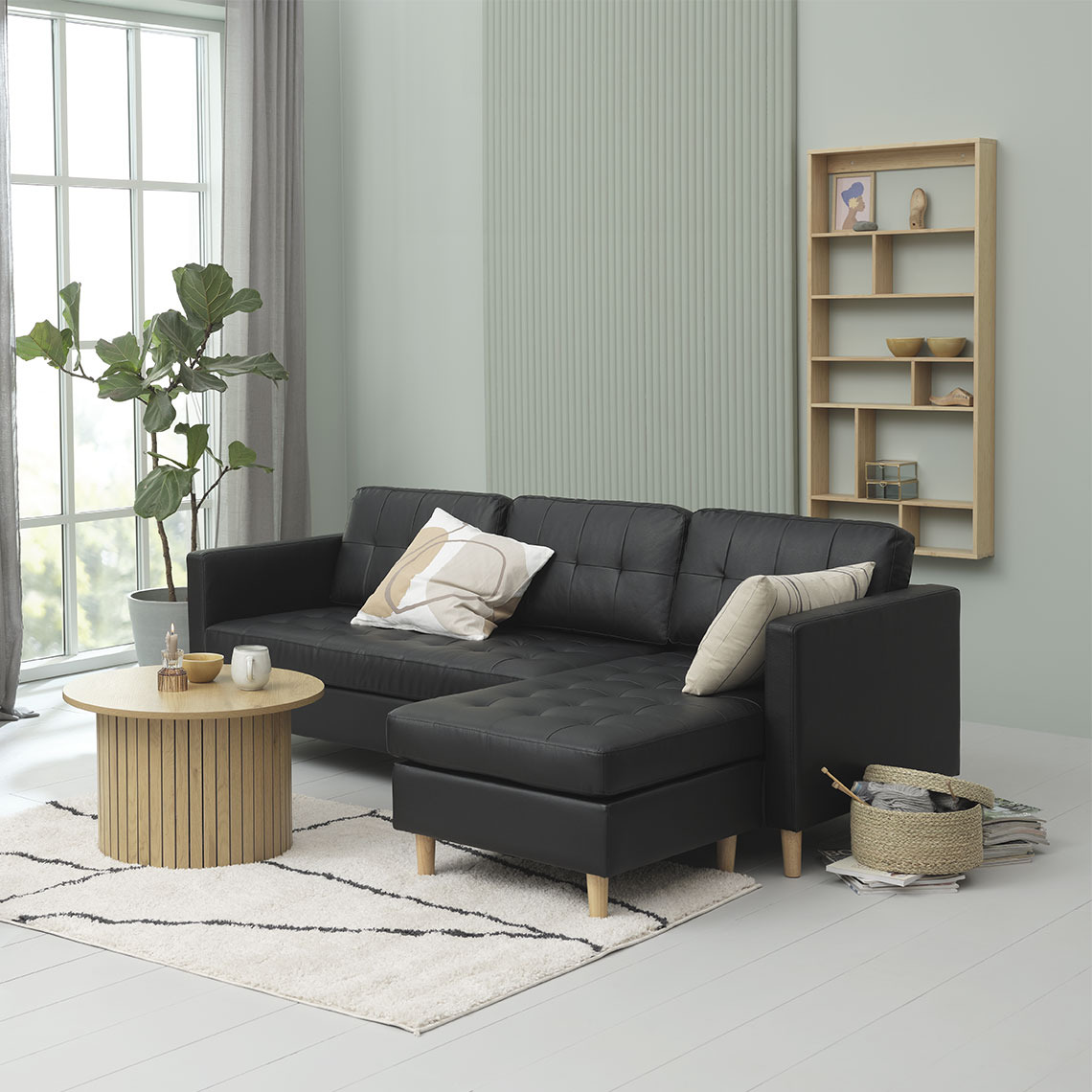 Black chaise lounge sofa in faux leather arranged with wooden furniture 