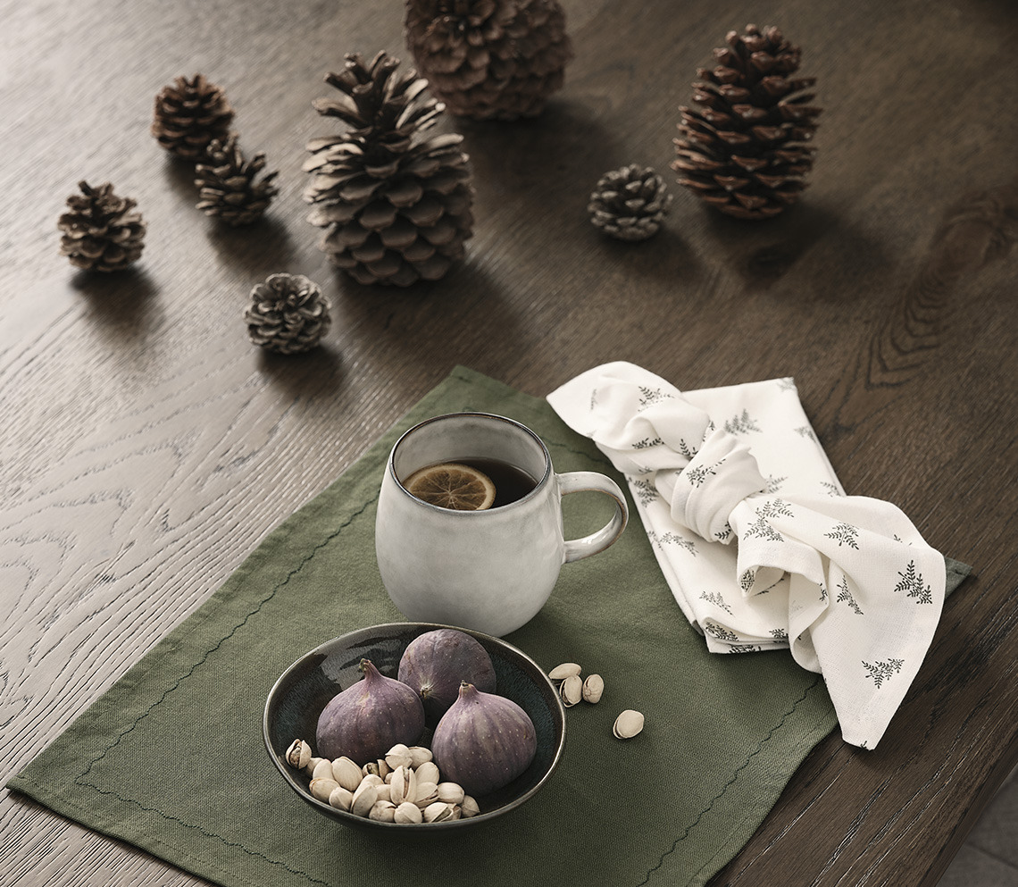 Table adorned with pinecones, placemat with bowl and mug