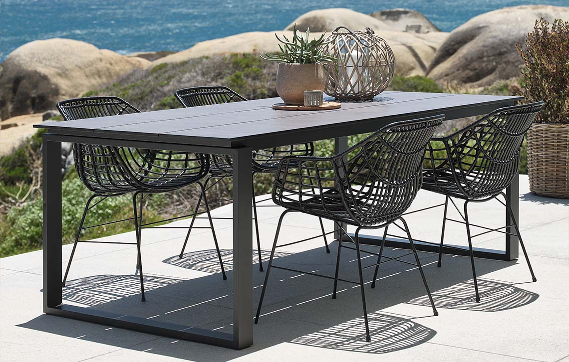 Garden table with table top made from composite wood and garden chairs on patio 