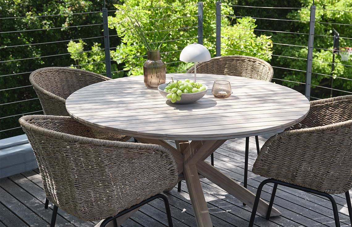 Garden table made from solid acacia on patio with garden chairs made with polyrattan and steel