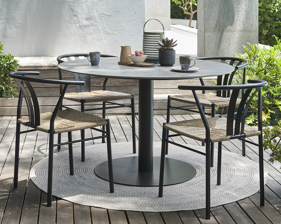 Grey VAMDRUP garden table and TAGMARK garden chairs Pedestal garden table with four garden chairs on a patio
