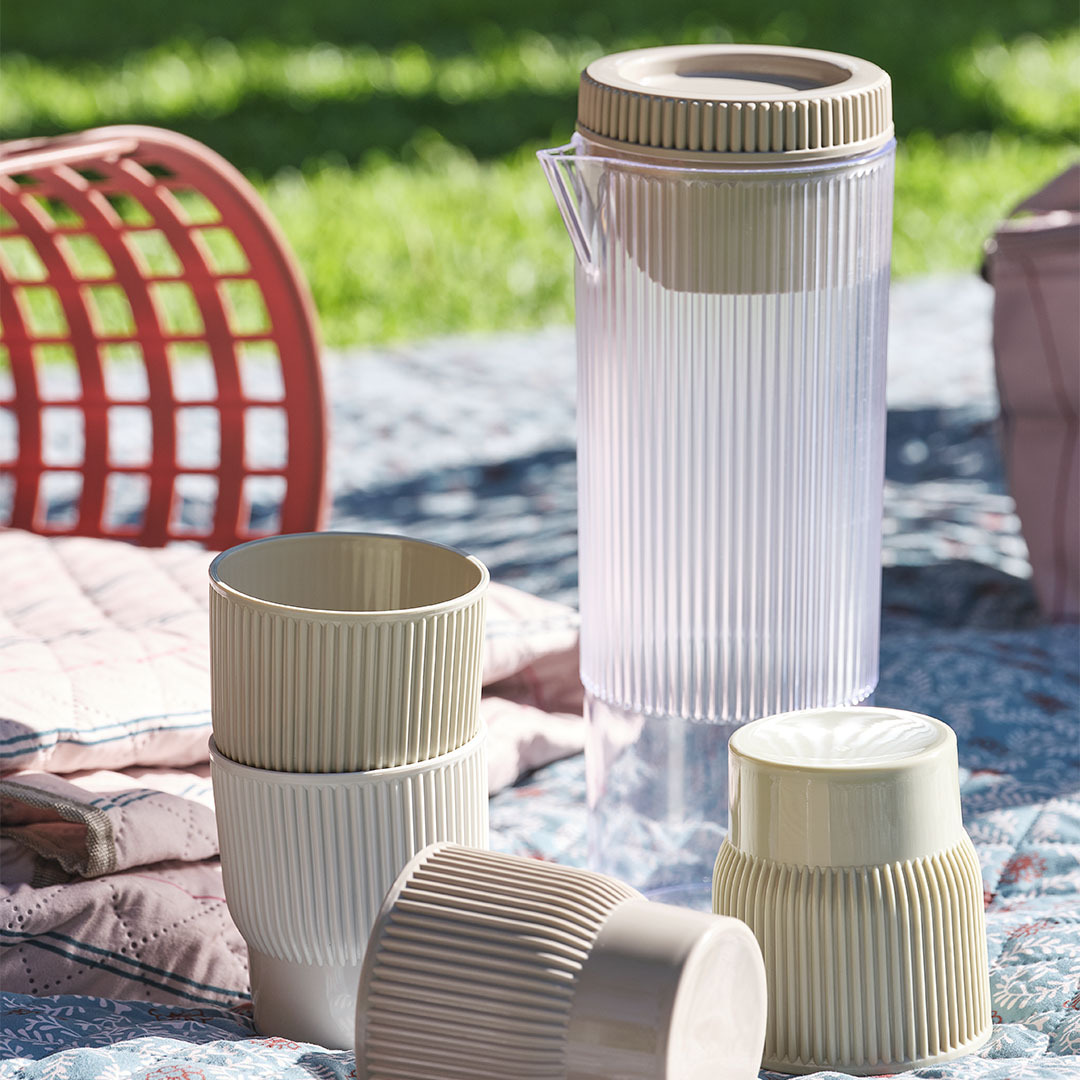 TJIM picnic jug with four matching cups Picnic essentials including a jug with four matching cups on a picnic blanket