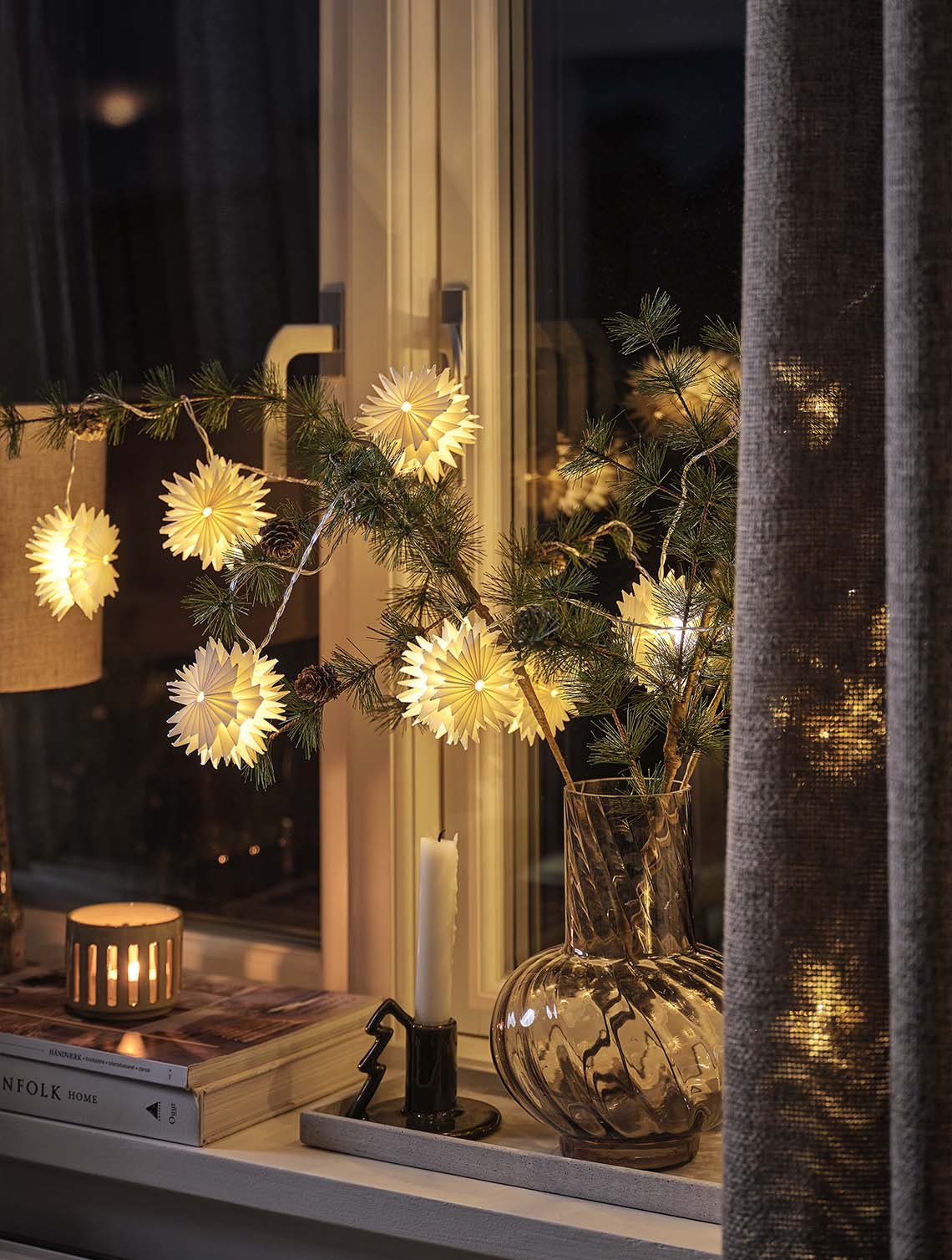 PLATIN star-shaped string lights with built-in timer Star-shaped string lights arranged on pine branches in a vase illuminating a windowsill at night