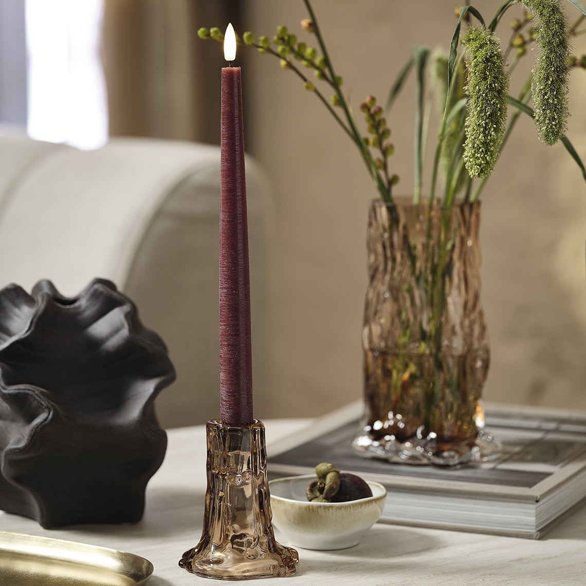 Glass vase and candlestick with purple candle on a coffee table