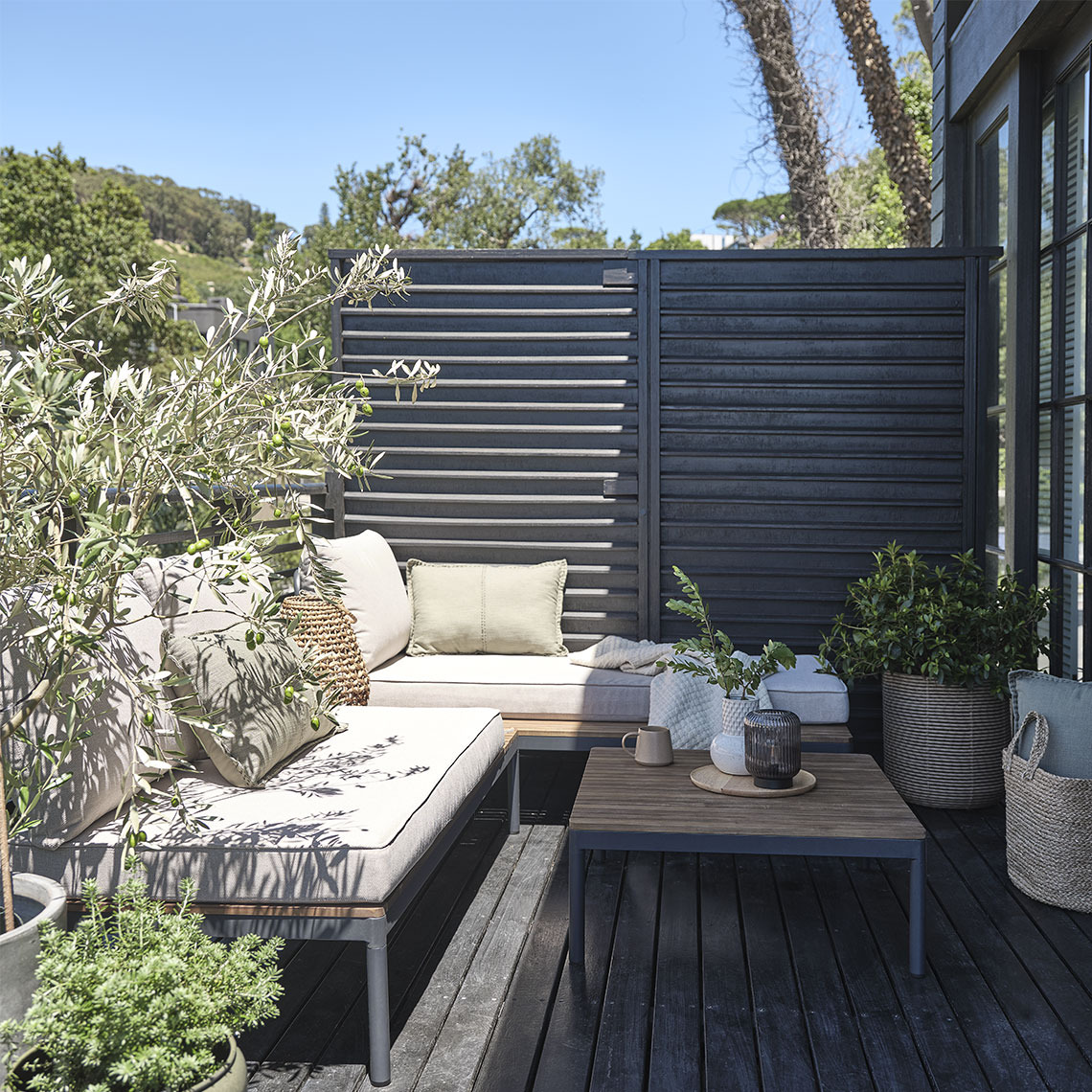 Garden lounge set on a small patio with plants and planters
