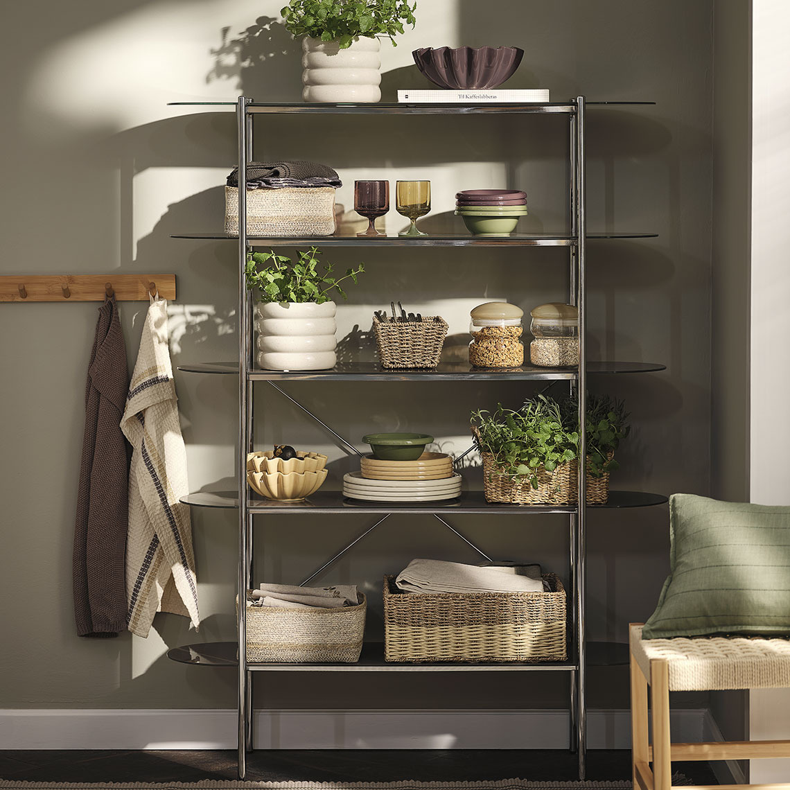 Colourful glasses, plates and bowls, baskets and storage jars on a shelving unit