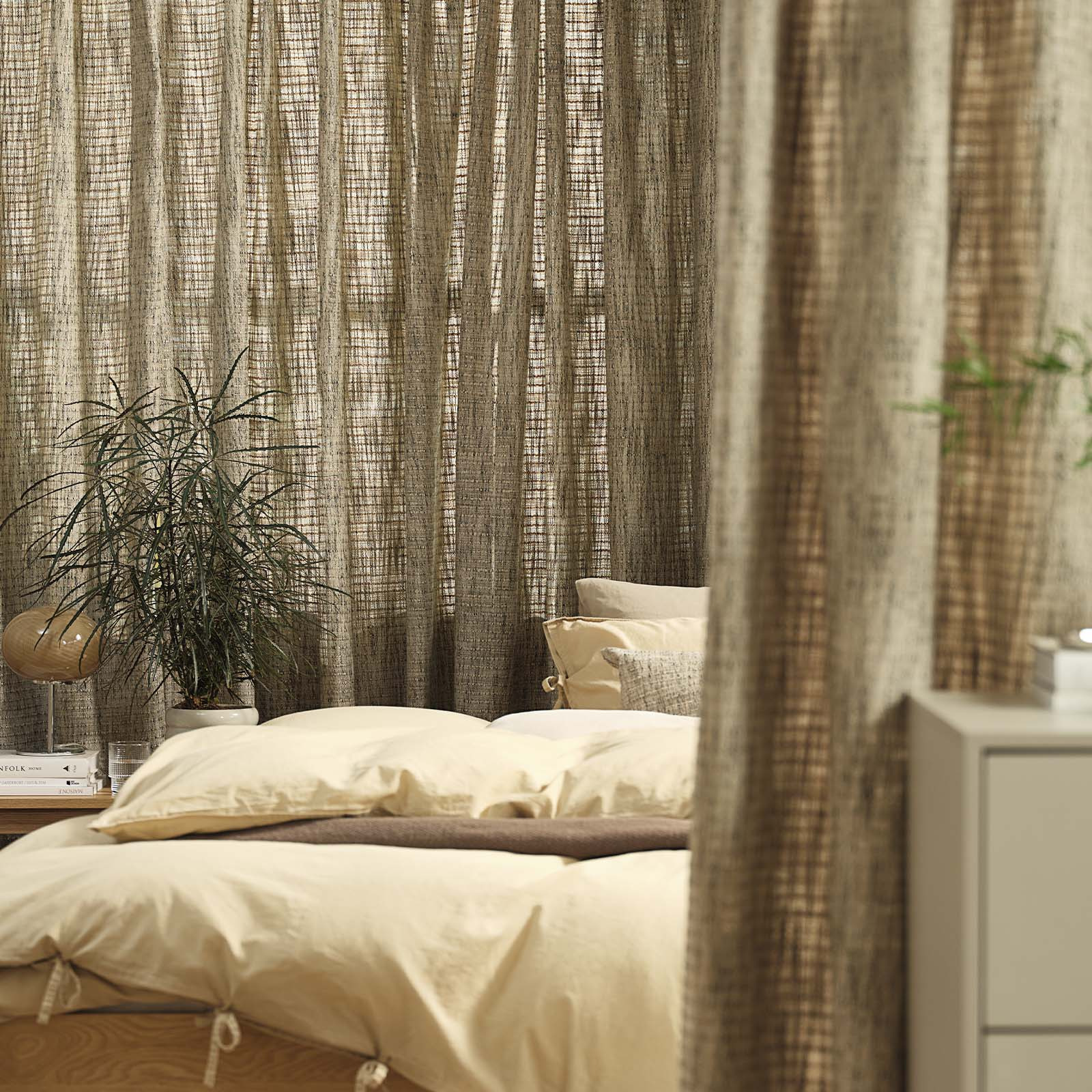 Window covered by a sandy green heavy curtain in bedroom