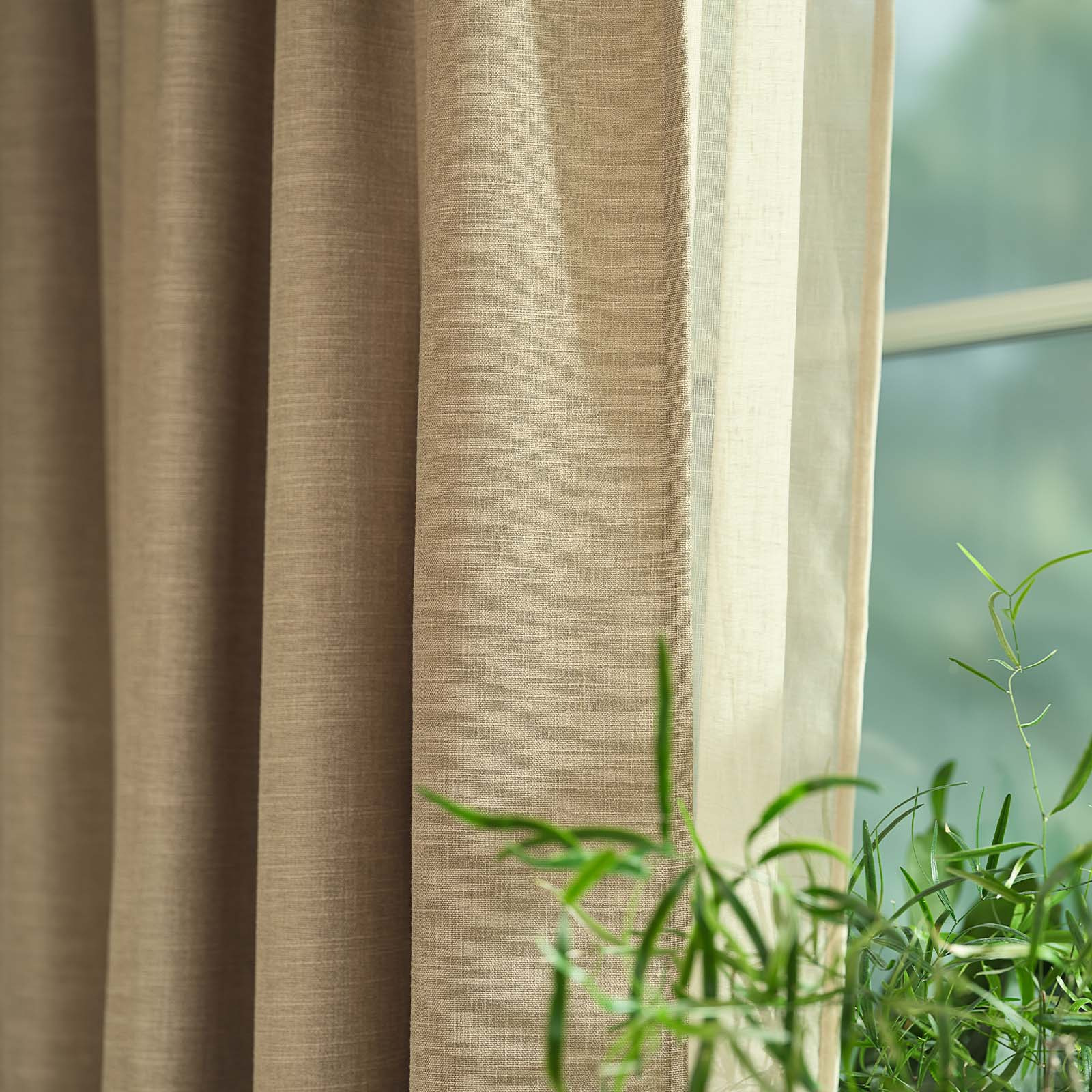 Close-up of a khaki, sandy-coloured heavy curtain in front of window